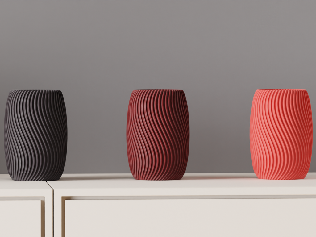 Three textured vases in black, red, and pink on a neutral surface with a gray background